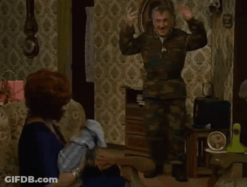 Man In Camouflage Standing In Front Of Seated Woman GIF
