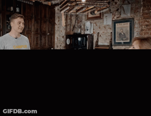 Man In Campus Shirt Talking To Woman At Bar GIF