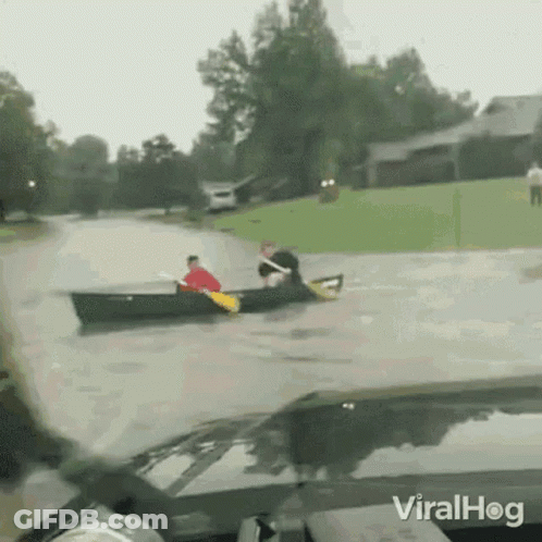 Man In Canoe Pulled By Car In Flooded Street GIF