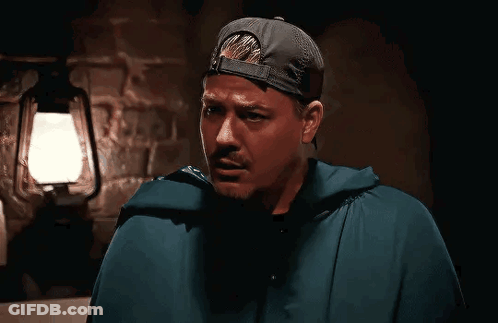 Man In Cape And Baseball Cap In Front Of Lantern GIF