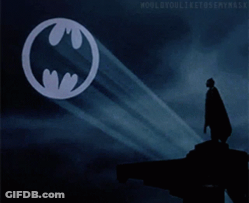 Man In Cape Standing Before Batman Symbol GIF