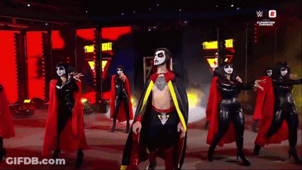 Man In Cape Surrounded By Women In Black And Red GIF