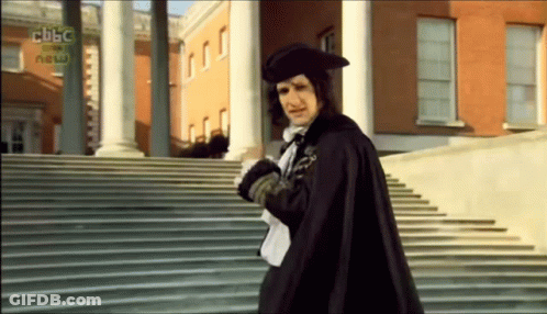 Man In Cape Walking Down Stairs In Front Of BBC News Building GIF