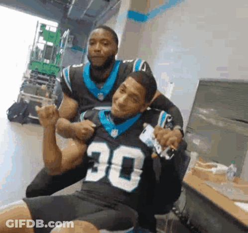 Man In Carolina Panthers Jersey Sitting With Another Man GIF