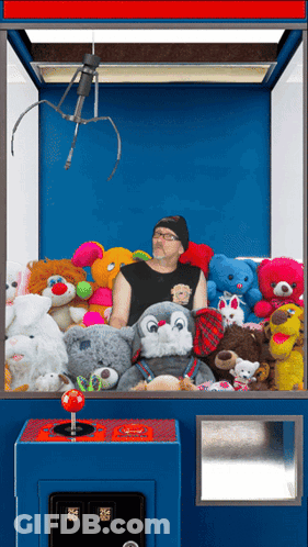 Man In Claw Machine With Stuffed Animals GIF
