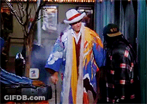 Man In Colorful Coat And Hat Next To Man In Black Jacket GIF