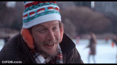 Man In Colorful Hat And Ear Muffs Looking At Camera GIF