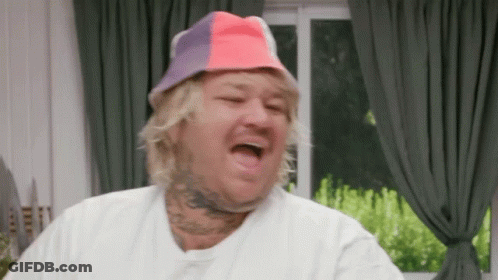 Man In Colorful Hat Making Funny Face In Living Room GIF