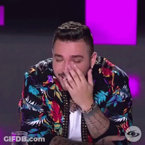 Man In Colorful Jacket Covering Face At Table GIF