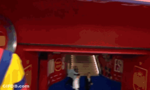 Man In Colorful Jacket In Front Of Coke Sign GIF