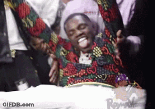 Man In Colorful Jacket Lying On Bed With Arms Outstretched GIF