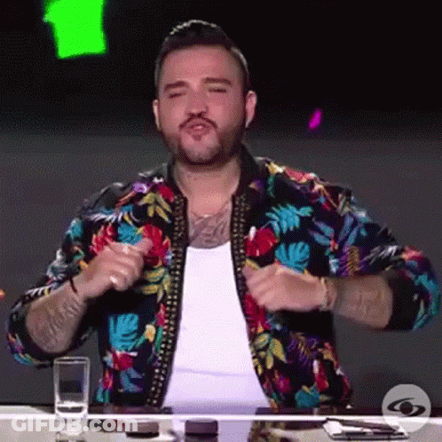Man In Colorful Jacket Sitting At Table GIF