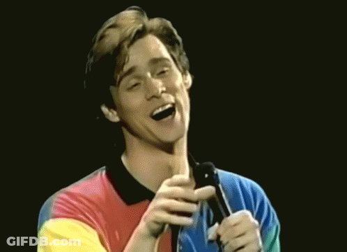 Man In Colorful Shirt Singing Into Microphone And Laughing GIF