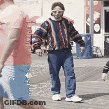 Man In Colorful Sweater And Sunglasses On Boardwalk GIF