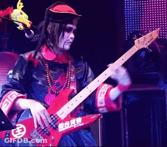 Man In Costume Playing Guitar With Chinese Characters GIF