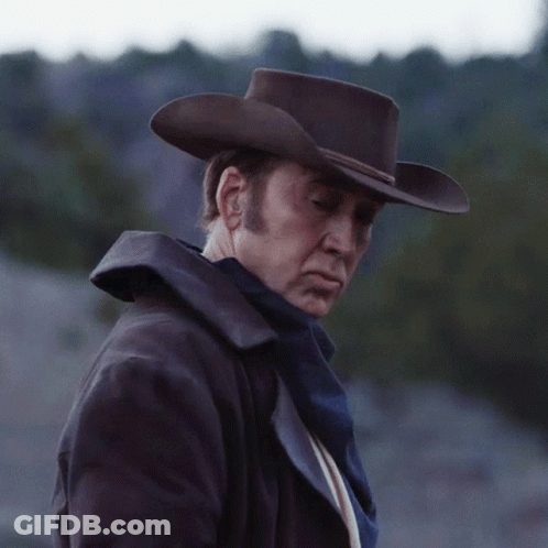 Man In Cowboy Hat And Coat Looks Down GIF