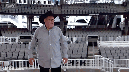 Man In Cowboy Hat And Glasses In Empty Stadium With AEW Logo GIF