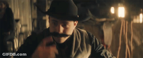 Man In Cowboy Hat And Mustache Sitting At Table GIF