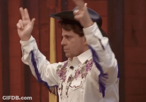 Man In Cowboy Hat And Purple Fringe Giving Peace Sign GIF