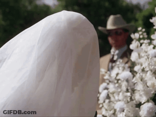 Man In Cowboy Hat Behind Bride In White Dress GIF