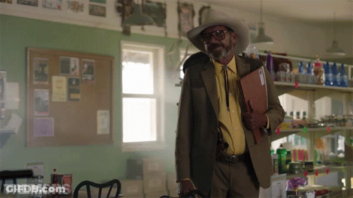 Man In Cowboy Hat Holding Folder With Tremors Sign GIF