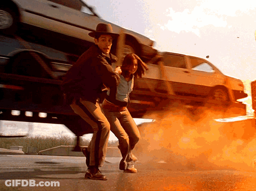 Man In Cowboy Hat Holding Woman In Front Of Stacked Cars GIF