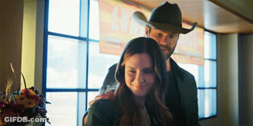 Man In Cowboy Hat Hugs Woman By Window GIF
