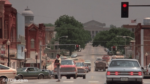 Man In Cowboy Hat On Busy Street With Red Light GIF