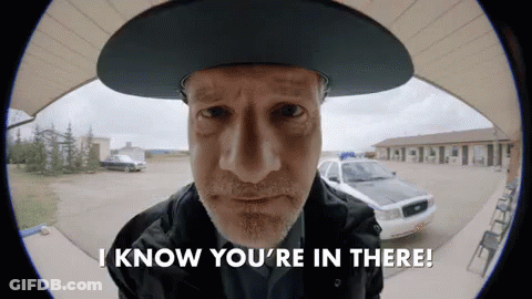 Man In Cowboy Hat Says I Know You're In There In Front Of Police Car GIF