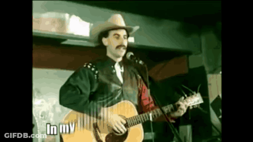 Man In Cowboy Hat Singing Into Microphone Holding Guitar GIF