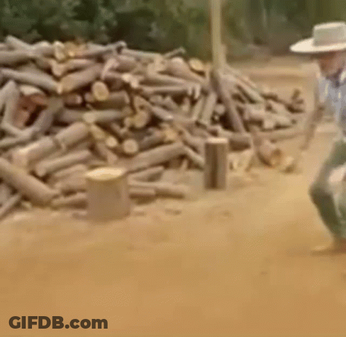 Man In Cowboy Hat Walking Near Log Pile GIF