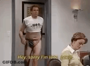 Man In Crop Top And Swim Trunks Standing In Doorway Next To Woman GIF