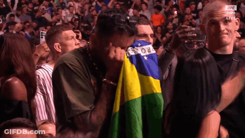 Man In Crowd Covering Face With Brazilian Flag GIF
