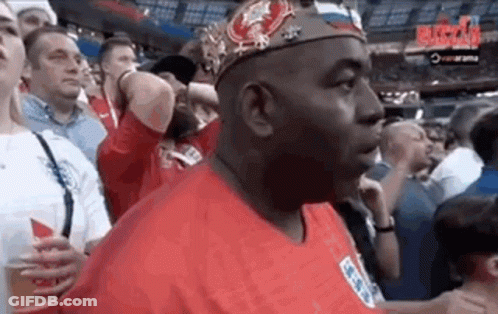 Man In Crown And Red Shirt Standing In Crowd GIF