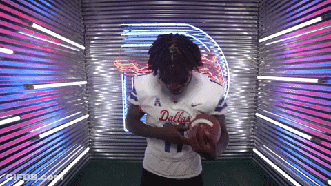 Man In Dallas Jersey Holding Football By Neon Sign GIF