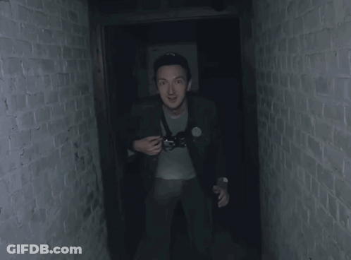 Man In Dark Hallway Holding Camera GIF