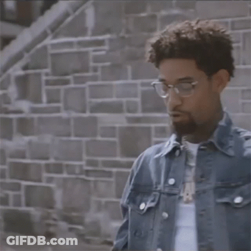 Man In Denim Jacket And Pearl Bracelets In Front Of Brick Wall GIF