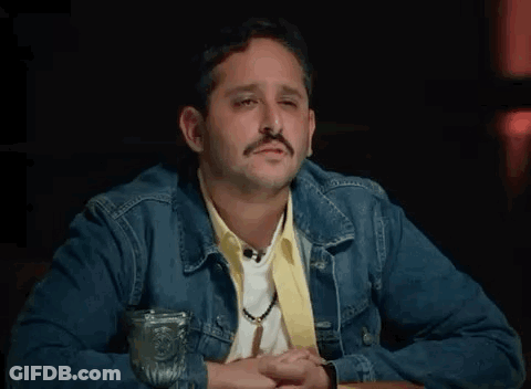 Man In Denim Jacket At Table With Water GIF