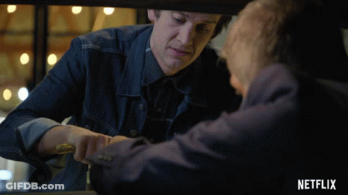 Man In Denim Jacket Holding Knife In Front Of Netflix Advertisement GIF