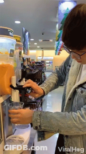 Man In Denim Jacket Pouring Orange Juice At Vending Machine GIF