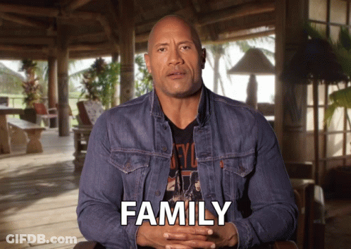 Man In Denim Jacket Sitting In Front Of Family Screen GIF