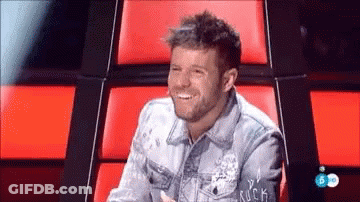 Man In Denim Jacket Smiling In Red Chair GIF