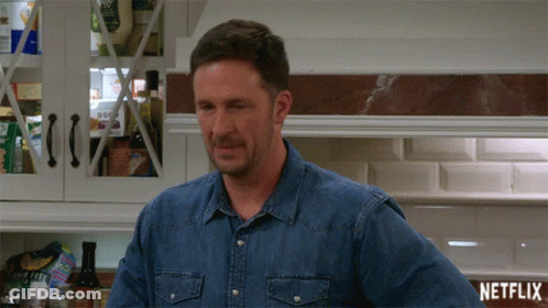 Man In Denim Shirt Next To Netflix Sign GIF