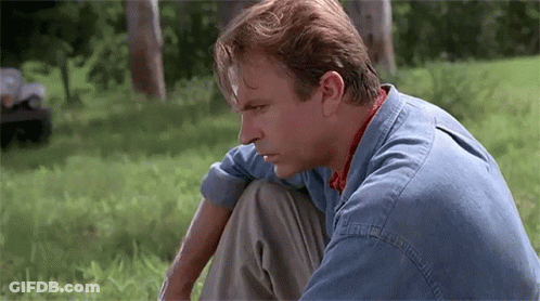 Man In Denim Shirt Sitting On Grass Looking Down GIF