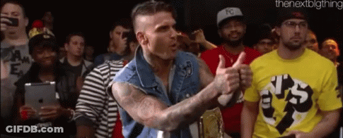 Man In Denim Vest Giving Thumbs Up In Crowd GIF