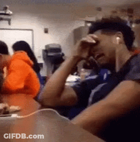Man In Earbuds Sitting With Hands On Face GIF