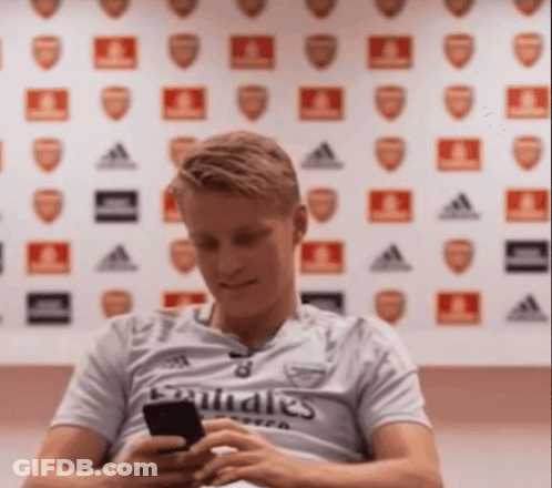 Man In Emirates Shirt Looking At Cell Phone GIF