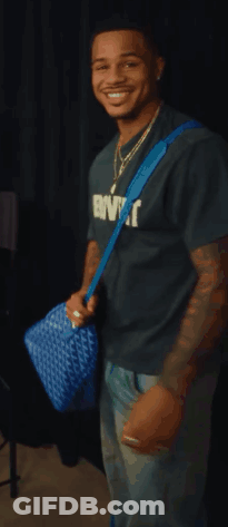 Man In Extrovert T-Shirt Smiling Holding Blue Bag GIF