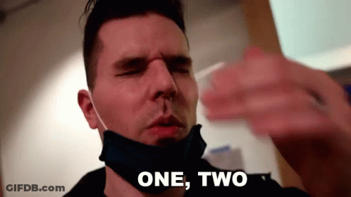 Man In Face Mask Taking Nose Swab Saying One Two GIF