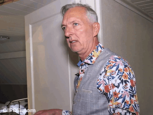 Man In Floral Shirt Standing In Front Of White Door GIF